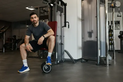 Homem sentado no aparelho de musculação, cansado