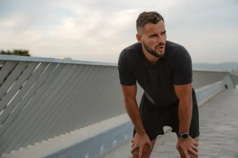 Homem descansando com as mãos nos joelhos